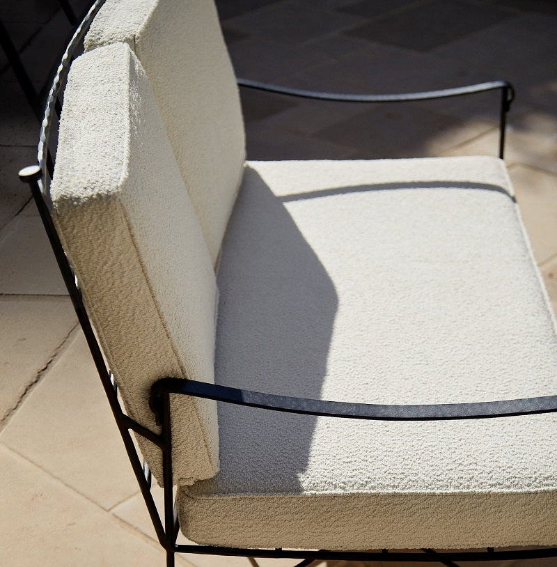 Main Image A stylish outdoor dining setting with a round table, white chairs, surrounded by lush greenery under a clear sky.
