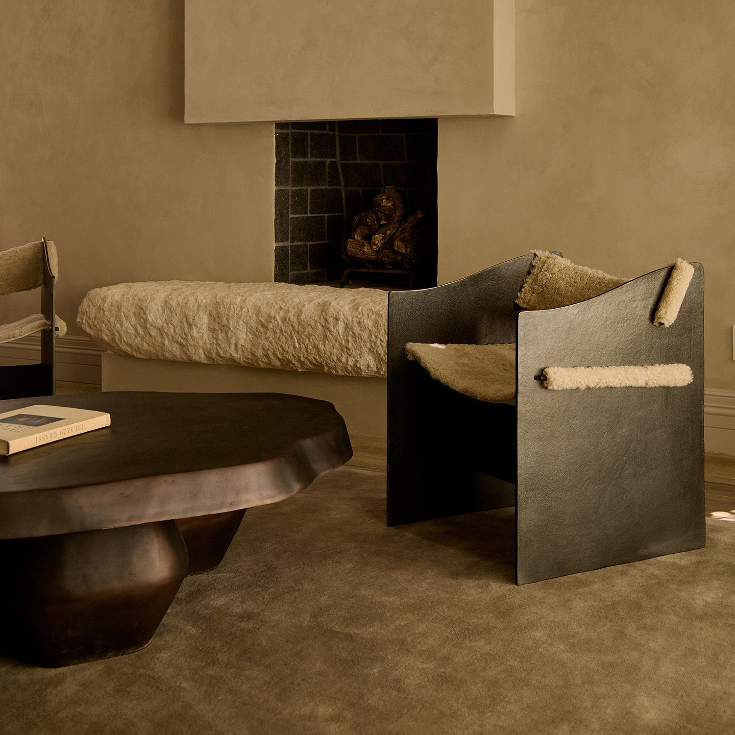 Main Image A stylish black chair with a furry seat, next to a round dark coffee table and a cozy fireplace with a rustic bench.