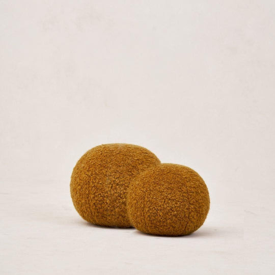 Two round, textured mustard-colored cushions in different sizes, placed against a neutral background.