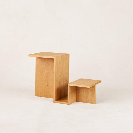 Minimalist wooden side tables with a geometric design, set against a neutral background.