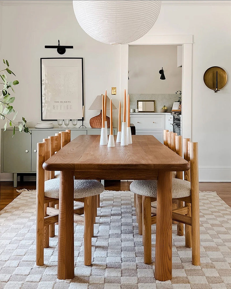 Minimalist dining room with a wooden table, matching chairs, tapered candles, and a paper lantern light.