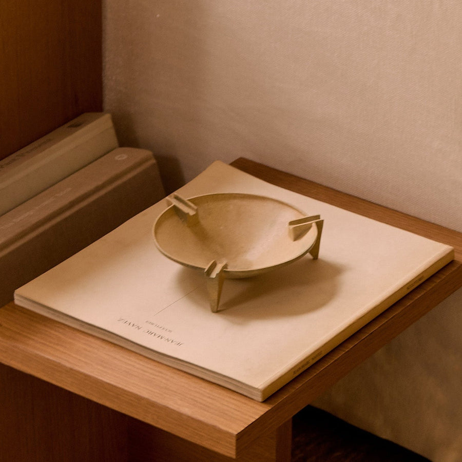 Wooden side table with a small tray and book next to a beige sofa.